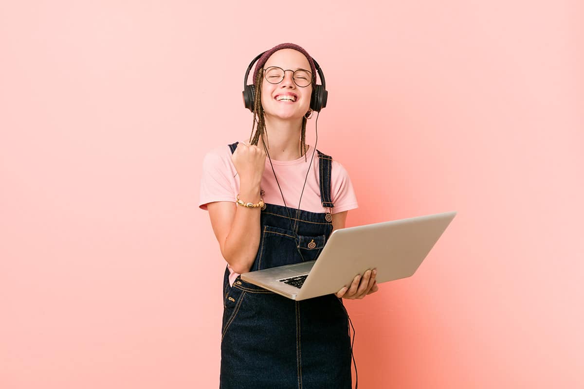 online learning student holding laptop cheering carefree